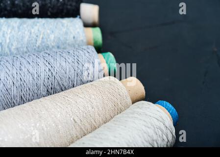 Set aus farbigem Garn zum Stricken auf Kegel auf schwarzem Hintergrund, Draufsicht Stockfoto