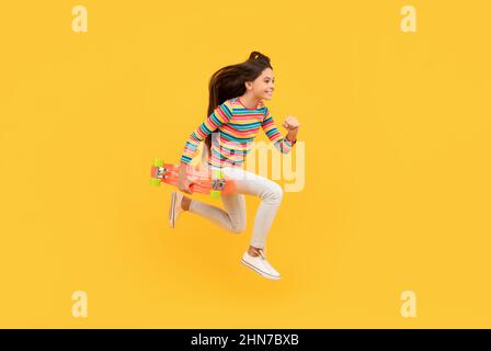 Glücklich energetische Kind Skateboarder springen mit Penny Board Skateboard, Kindheit Stockfoto