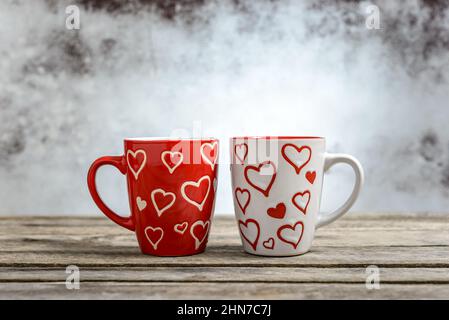 Kaffeetassen mit Herzformen auf rustikalem Holztisch. Romantisches Konzept zum Valentinstag. Stockfoto