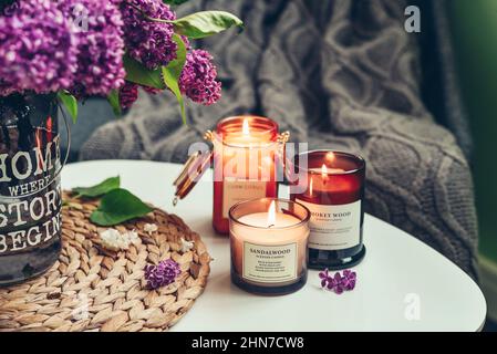 Bouquet von lila Flieder Blumen auf Couchtisch mit brennenden Kerzen im Inneren des Hauses Stockfoto