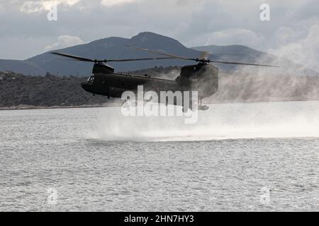 Ein US Army CH-47 Chinook, der dem U.S. Special Operations Command Europe zugewiesen wurde, landet im Mittelmeer, während er ein Joint Combined Exercise Training (JCET) mit griechischen Spezialeinheiten am 24. November 2021 in Athen, Griechenland, durchführt. Das JCET ist eine Demonstration griechischer Spezialkriegseinheiten und US-Spezialeinsatzkräfte, die sich für schnelle Eingreifenmissionen im gesamten Mittelmeer koordinieren. Stockfoto