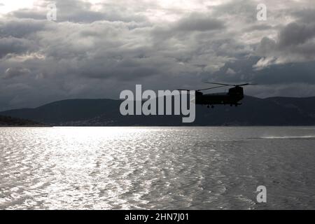 Ein US Army CH-47 Chinook, der dem U.S. Special Operations Command Europe zugewiesen wurde, landet im Mittelmeer, während er ein Joint Combined Exercise Training (JCET) mit griechischen Spezialeinheiten am 24. November 2021 in Athen, Griechenland, durchführt. Das JCET ist eine Demonstration griechischer Spezialkriegseinheiten und US-Spezialeinsatzkräfte, die sich für schnelle Eingreifenmissionen im gesamten Mittelmeer koordinieren. Stockfoto