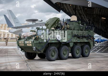 SPC der US-Armee. Jordan Oosting und Maj. Michael Anderson beladen ein Stryker-Kampffahrzeug von einem 62nd Airlift-Flügel C-17 Globemaster III auf der Andersen Air Force Base, Guam, 6. Februar 2022. Mitglieder des ersten amerikanischen Korps, die von der Joint Base Lewis-McChord nach Guam entsandt wurden, um eine Trainingsübung durchzuführen, die die Bereitschaft verbessert, die gemeinsame Interoperabilität demonstriert und verteilte Missionsbefehle im Pazifik ausübt. (USA Armee-Foto von SPC. Jailene Bautista, 5th Mobile Public Affairs Detachment) Stockfoto