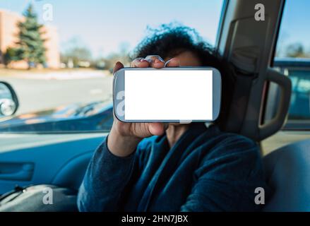 Modell der Telefonanwendung im Auto. Weibliche Hand hält den weißen leeren Bildschirm des Mobiles. Text für Leerzeichen kopieren. Selektiver Fokus. Stockfoto