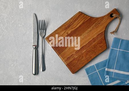 Braunes Holzschneidebrett mit Besteck und Servietten zum Abendessen Stockfoto