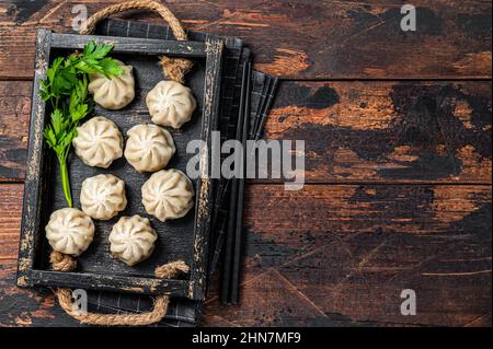 Momo Knödel in einem Holztablett mit Kräutern. Dunkler Holzhintergrund. Draufsicht. Speicherplatz kopieren Stockfoto