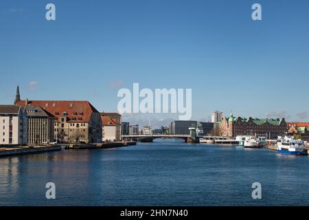 KOPENHAGEN, DÄNEMARK - 30. APRIL 2017: Blick auf die Uferpromenade von Christianshavn auf der linken Seite und auf die Gebäude und Boote der Börse Tietgens Hus und Borsen auf der rechten Seite. Stockfoto