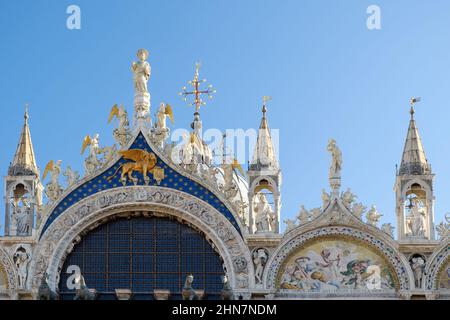 Architektonische Details aus dem oberen Teil der Fassade des Markusbasilika in Venedig, Italien. Sonniger Tag, blauer Himmel. Stockfoto