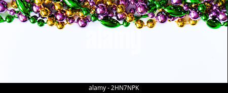 Mardi Gras Hintergrund. Bunte Perlen auf weißem Hintergrund. Fat Tuesday-Symbol. Festliche Dekorationen in Gold, Grün und Lila für Traditiona Stockfoto