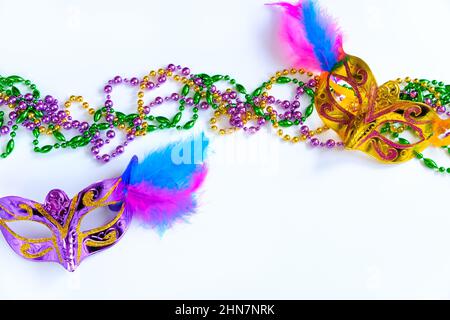 Zwei Karnevalsmasken mit Federn und bunten Perlen auf weißem Hintergrund. Symbol „Mardi Gras“ oder „Fat Tuesday“. Grußkarte für traditionelle holi Stockfoto