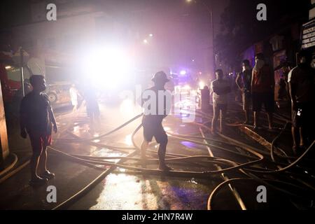 Manila, Philippinen. 14th. Februar 2022. Ein Feuerwehrmann arbeitet entlang einer Straße, während er ein Feuer kontrolliert, das am Montagabend ein Wohngebiet in Quezon City, Philippinen, erfasst hat. 14. Februar 2022. Die Behörden versuchen immer noch, die Ursache des Feuers zu ermitteln, der mehrere Häuser zerstört hat. (Bild: © Basilio Sepe/ZUMA Press Wire) Stockfoto