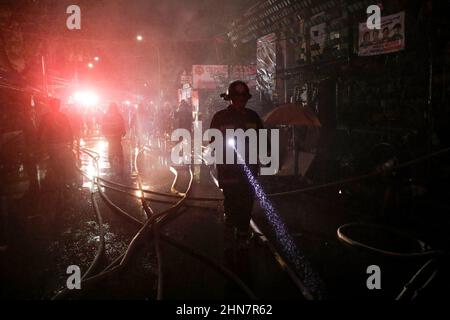 Manila, Philippinen. 14th. Februar 2022. Ein Feuerwehrmann arbeitet entlang einer Straße, während er ein Feuer kontrolliert, das am Montagabend ein Wohngebiet in Quezon City, Philippinen, erfasst hat. 14. Februar 2022. Die Behörden versuchen immer noch, die Ursache des Feuers zu ermitteln, der mehrere Häuser zerstört hat. (Bild: © Basilio Sepe/ZUMA Press Wire) Stockfoto