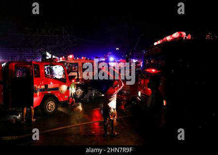 Manila, Philippinen. 15th. Februar 2022. Bewohner retten ihre Sachen, während Feuerwehrleute am Montagabend ein Feuer kontrollieren, das ein Wohngebiet in Quezon City, Philippinen, umschlingte. 14. Februar 2022. Die Behörden versuchen immer noch, die Ursache des Feuers zu ermitteln, der mehrere Häuser zerstört hat. (Bild: © Basilio Sepe/ZUMA Press Wire) Stockfoto