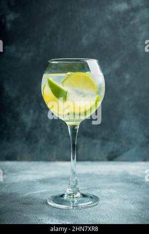 Cocktail auf Rum-Basis mit Limette im Weinglas (Variante cuba libre) auf rustikalem Hintergrund. Selektiver Fokus. Geringe Schärfentiefe. Stockfoto