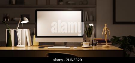 Moderne dunkle private Büroraum oder Home-Office-Arbeitsplatz in der Nacht mit pc-Desktop-Computer weißen Bildschirm mockup und liefert auf dem Tisch unter Licht f Stockfoto
