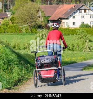 Radtour mit Buggy zwischen blühenden Bäumen im Frühling Stockfoto