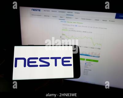 Person, die ein Mobiltelefon mit dem Logo des finnischen Ölunternehmens Neste Oyj auf dem Bildschirm vor der Business-Webseite hält. Konzentrieren Sie sich auf die Telefonanzeige. Stockfoto