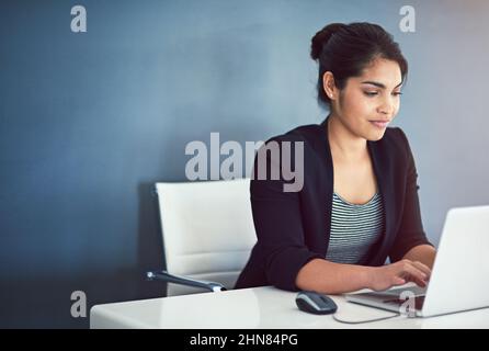 Shes ein engagierter junger Mitarbeiter. Eine kurze Aufnahme einer attraktiven jungen Geschäftsfrau, die in ihrem Büro an einem Laptop arbeitet. Stockfoto