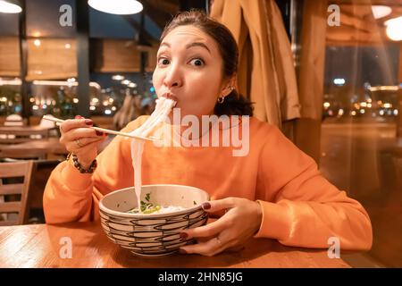 Asiatische Frau, die im Restaurant vietnamesische Nudelsuppe mit Essstäbchen isst Stockfoto