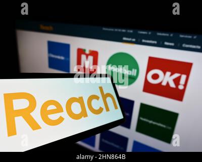 Smartphone mit Logo des britischen Verlags REACH plc auf dem Bildschirm vor der Unternehmenswebsite. Konzentrieren Sie sich auf die Mitte links des Telefondisplays. Stockfoto