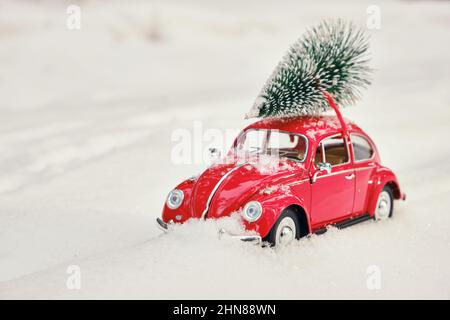 Kostanay, Kasachstan 2022.Roter Volkswagen Käfer mit Fichte auf dem Dach, vor Hintergrund weißem Schnee Stockfoto