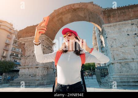 Glückliche Reisende Student Mädchen macht Selfie-Foto und genießt Blick auf Galerie Arch in Thessaloniki Stadt in Griechenland Stockfoto