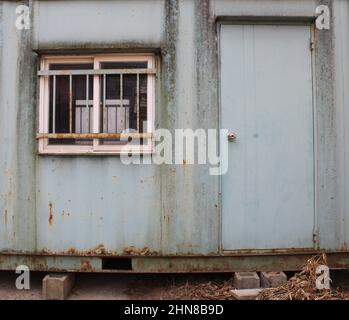 Verwittertes grünes Transportcontainer-Büro in der Nähe der Baustelle Stockfoto