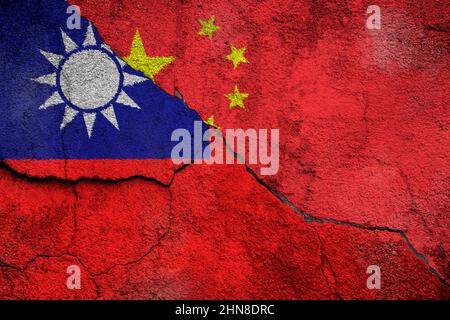 Vollformatfoto einer verwitterten Flagge Taiwans (ROC) und Chinas (PRC) auf einer rissigen Wand. Cross-Strait-Beziehungen und Konfliktkonzept. Stockfoto