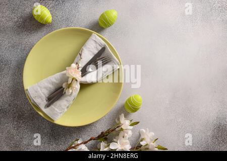 Ostern festliche Tischgestaltung mit Frühlingsgrün Dekoration und bunten Eiern. Blick von oben. Speicherplatz kopieren. Stockfoto