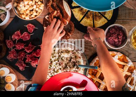 Oben Ansicht der Hände Menschen, die Nahrung vom Tisch nehmen. Menschen in Freundschaft essen zusammen zu Mittag. Gemischtes Essen auf dem Tisch. Vertikale Nahaufnahme von fr Stockfoto