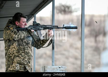 REGION SAPORISCHSCHSCHJA, UKRAINE - 14. FEBRUAR 2022 - Oleksandr Starukh, Leiter der regionalen Staatsverwaltung Zaporischschschja, schießt ein Gewehr auf eine Schießerei Stockfoto