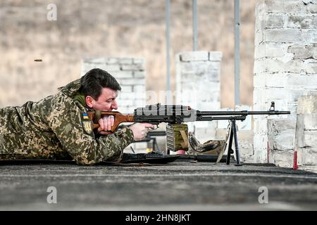 REGION SAPORISCHSCHSCHJA, UKRAINE - 14. FEBRUAR 2022 - der Leiter der regionalen Staatsverwaltung Zaporischschschja Oleksandr Starukh schießt ein Maschinengewehr auf einen Stockfoto