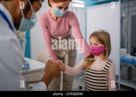 Kleines Mädchen mit ihrer Mutter in der Arztpraxis auf Konsultation, Coronavirus-Konzept. Stockfoto