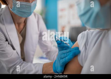 Nahaufnahme eines jungen Mannes, der von seinem Arzt in der Klinik eine covid-19-Impfung erhalten hat. Stockfoto