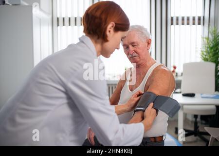 Ärztin, die den Blutdruck an eine ältere Patientin in ihrem Büro misst. Stockfoto
