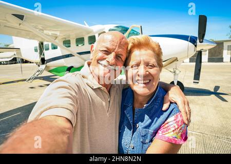 Ein glückliches Paar mit Senioren, das Selfie mit einem privaten Ultraleichtflugzeug macht, um die Welt zu bereisen - ein Konzept für aktive ältere Menschen mit pensio-Genuss im Ruhestand Stockfoto