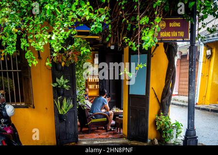 Ein paar Leute sitzen in einem kleinen Eckcafe in der Altstadt, Hoi an, und trinken Kaffee. Stockfoto