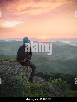 Allein Tourist am Rande des Berghügels gegen Die Kulisse eines unglaublichen Sonnenuntergangs Berglandschaft Stockfoto