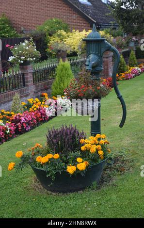 Farbenfrohe Blumengrenze, Töpfe und Wasserpumpe im Vorgarten, suffolk, england Stockfoto