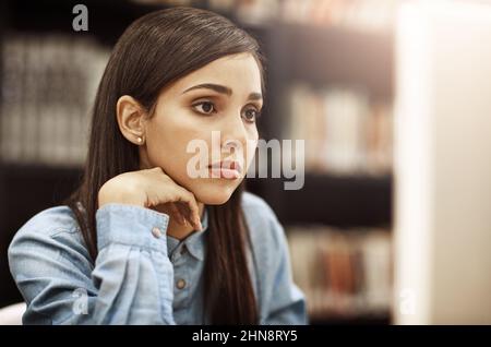 Konzentriert sich auf ihre glänzende und erfolgreiche Zukunft. Aufnahme eines Studenten, der an einem Computer in der Bibliothek auf dem Campus arbeitet. Stockfoto