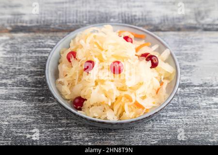 Sauerkraut, marinierter Kohl auf einer blauen Keramikplatte auf grauem Holzgrund. Seitenansicht, Nahaufnahme. Stockfoto