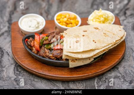 Fleisch Fajitas auf schwarzem Steinteller mit Saucen Stockfoto