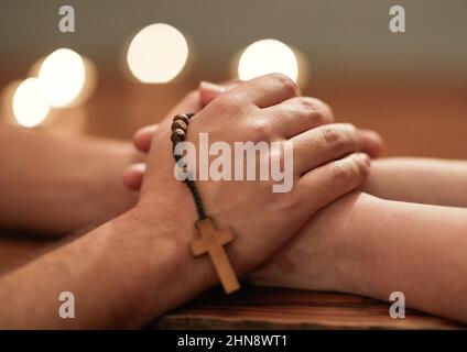 Hände sind da, um anderen zu helfen. Ein kurzer Schuss von zwei Menschen, die die Hände halten und zusammen beten. Stockfoto