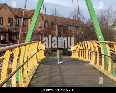 Mann, der über die farbenfrohe Wigg-Fußgängerbrücke geht, die den Fluss Nene in Southbridge, Northampton, Großbritannien, überquert Stockfoto