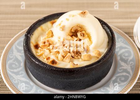 Türkischer Sutlac- oder Ofenreis-Pudding mit Haselnüssen in Tonschüssel. Stockfoto