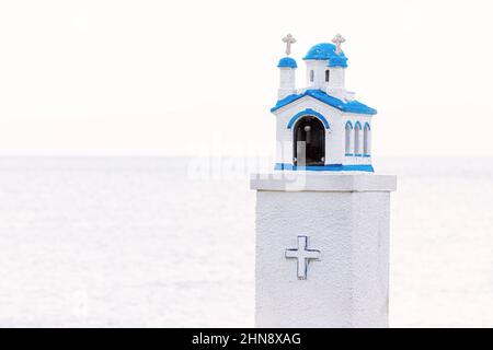 Proskinitari - eine kleine Kopie einer griechisch-orthodoxen Kirche, die an der Seite einer malerischen Seestraße installiert ist. Traditioneller Ort der Anbetung und Wallfahrt in Stockfoto