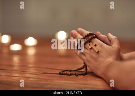 Das Gebet kann alles verändern. Ausgeschnittene Aufnahme eines Mannes, der einen Rosenkranz hält und betet. Stockfoto