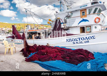 25. Oktober 2021, Neos Marmaras, Griechenland: Ein Fischerboot und ein großer Haufen Netz auf dem Pier zum Trocknen und Reparieren Stockfoto