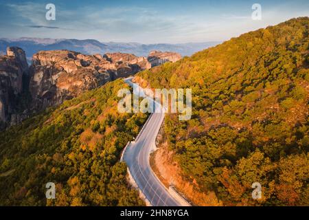 Luftaufnahme von oben über malerische Serpentinenstraßen inmitten eines dichten Waldes in der Nähe von Meteora-Klöstern in Griechenland Stockfoto