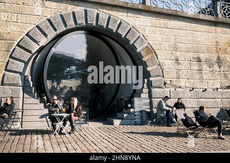 Eine Café-Bar am Flussufer mit einer großen runden Glastür in Prag. Stockfoto